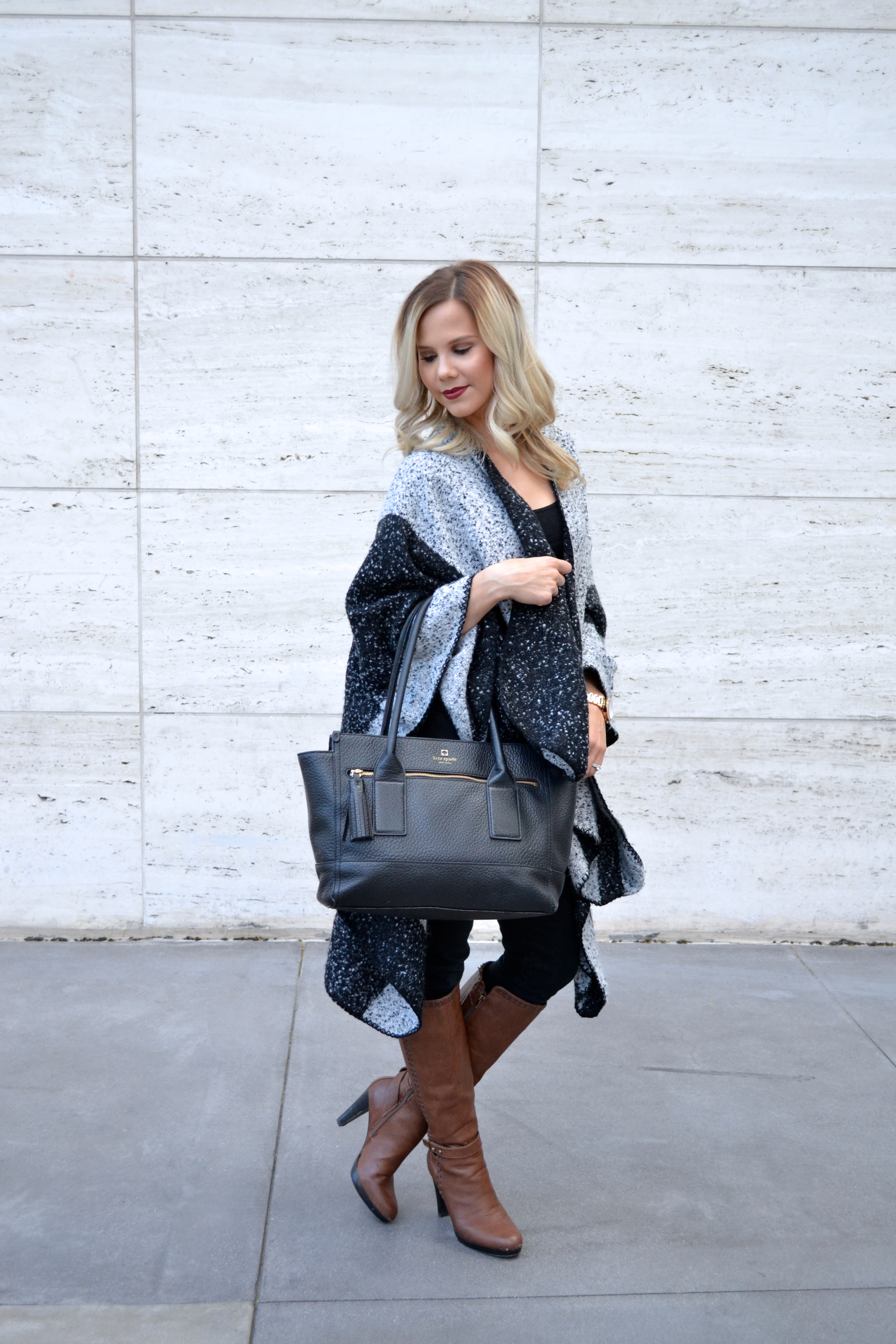 black and grey poncho, black jeans, boots, and Black Kate Spade Tote