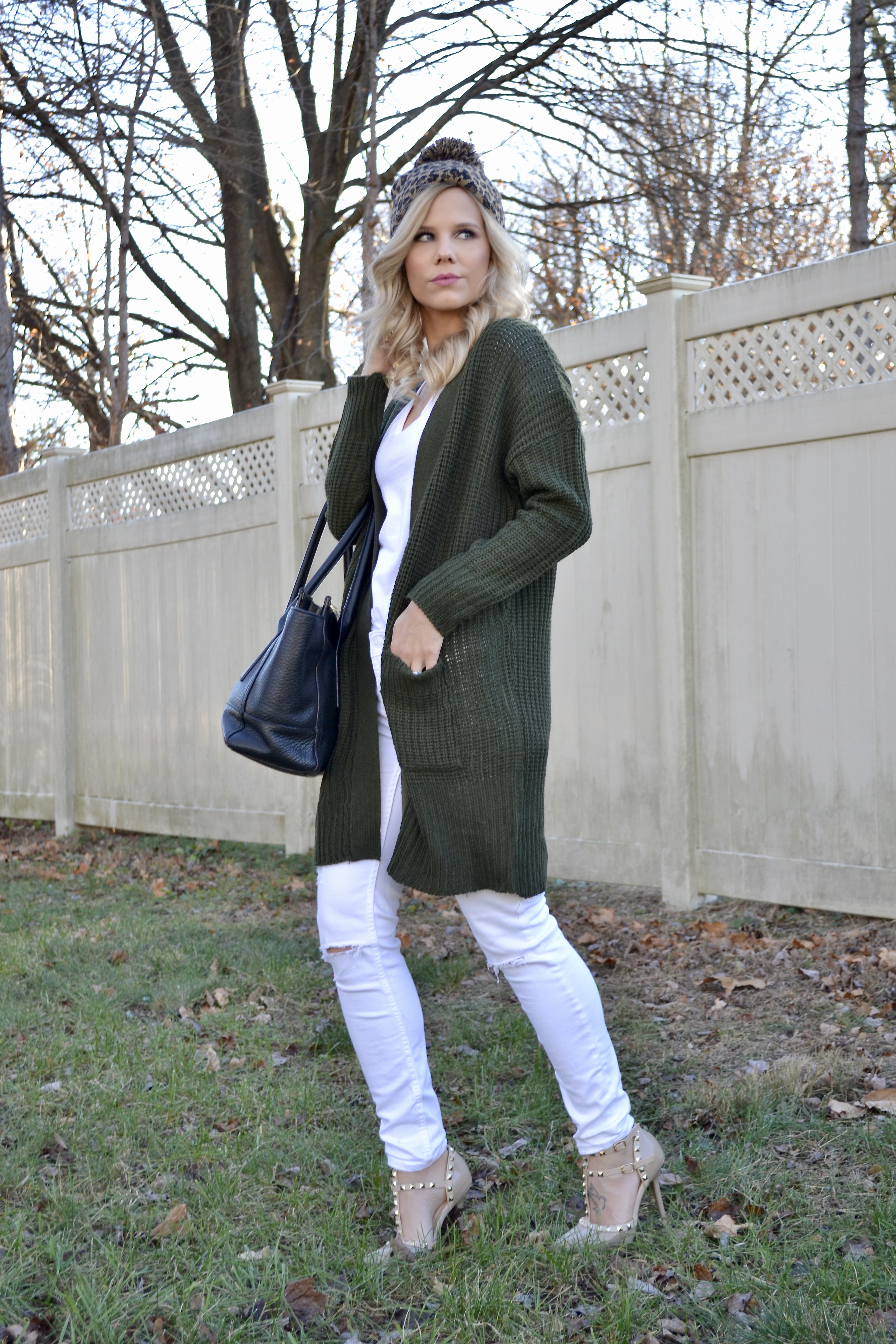green cardigan, white jeans, cheetah beanie with pom on glam life living 