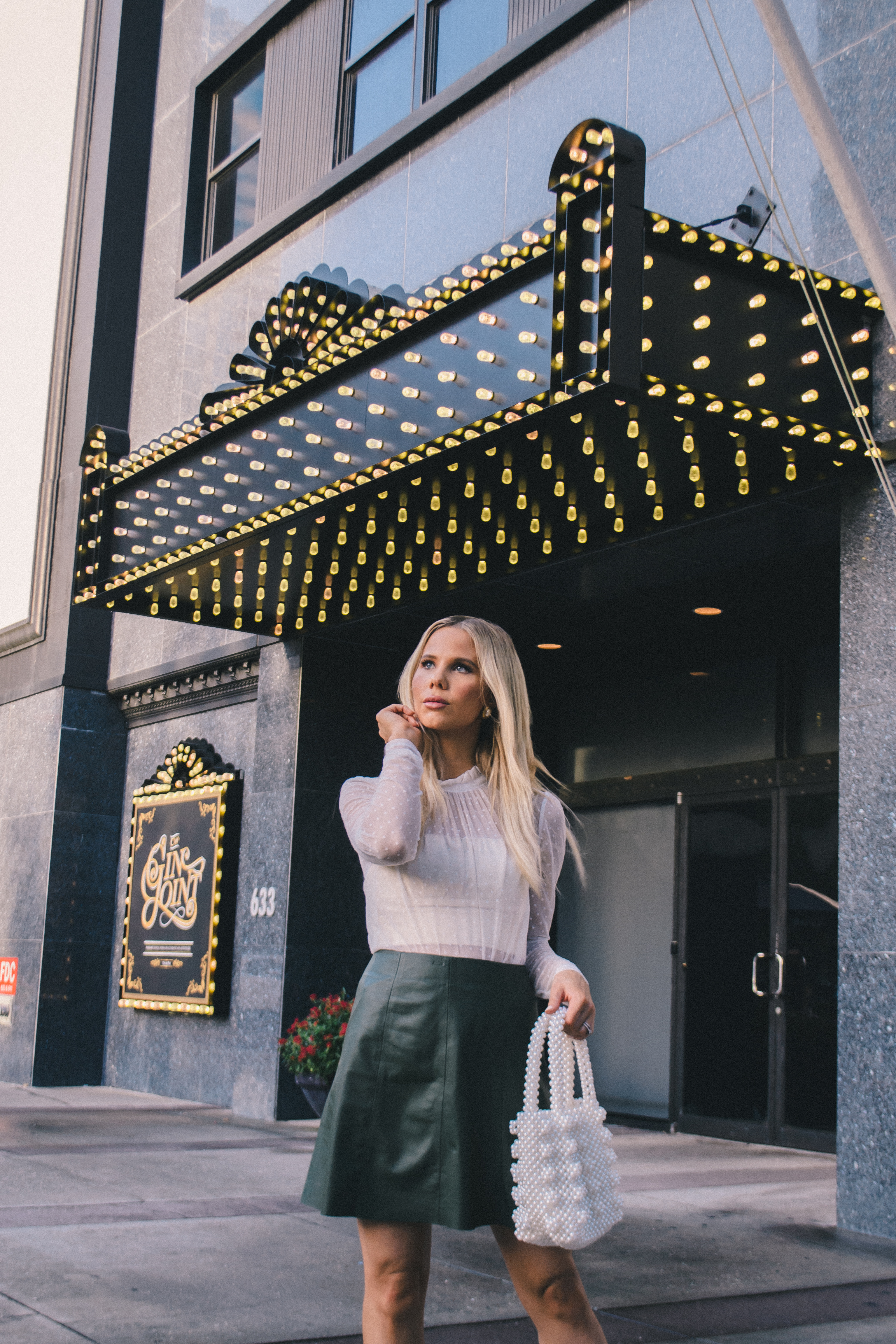 french date night outfit, feminine romantic style, green leather skirt, high neck blouse 